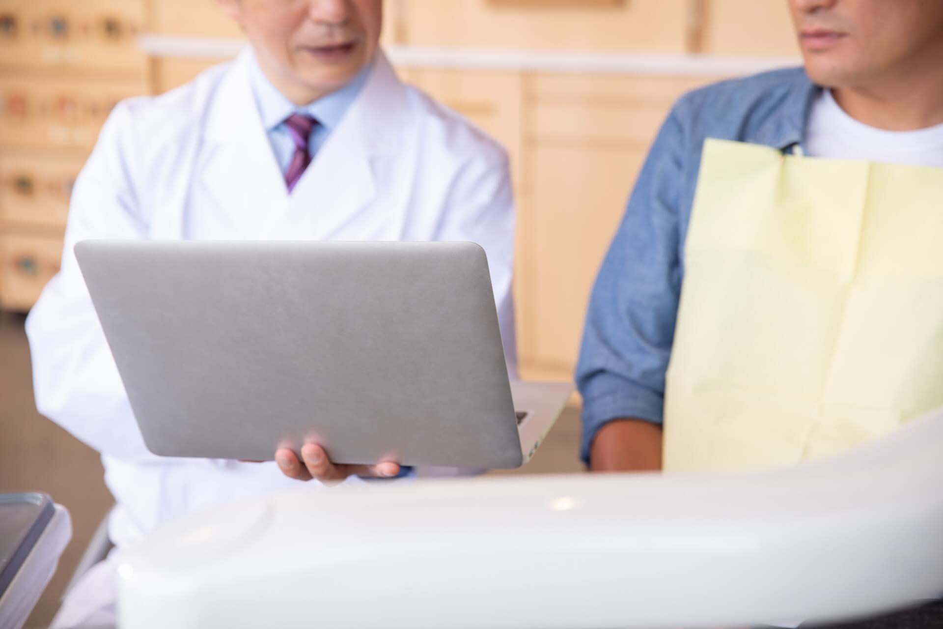 患者にカルテを見せる歯科医師